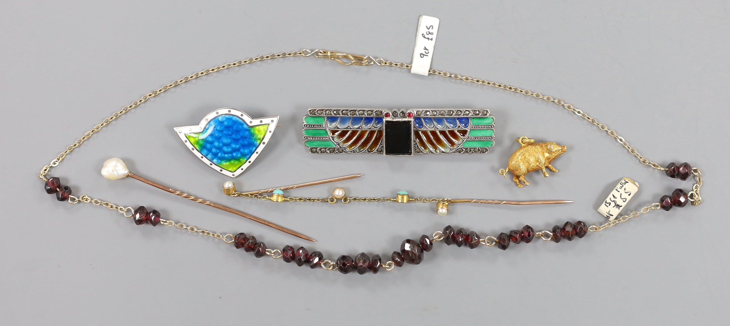 An Art Deco white metal, plique a jour, black onyx and marcasite set rectangular brooch, 54mm, a three colour enamelled brooch, a yellow metal and facetted garnet bead necklace, a 9ct pig charm and, a cloak pin? and a ba